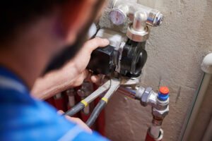Male plumber installing heating radiator in apartment.